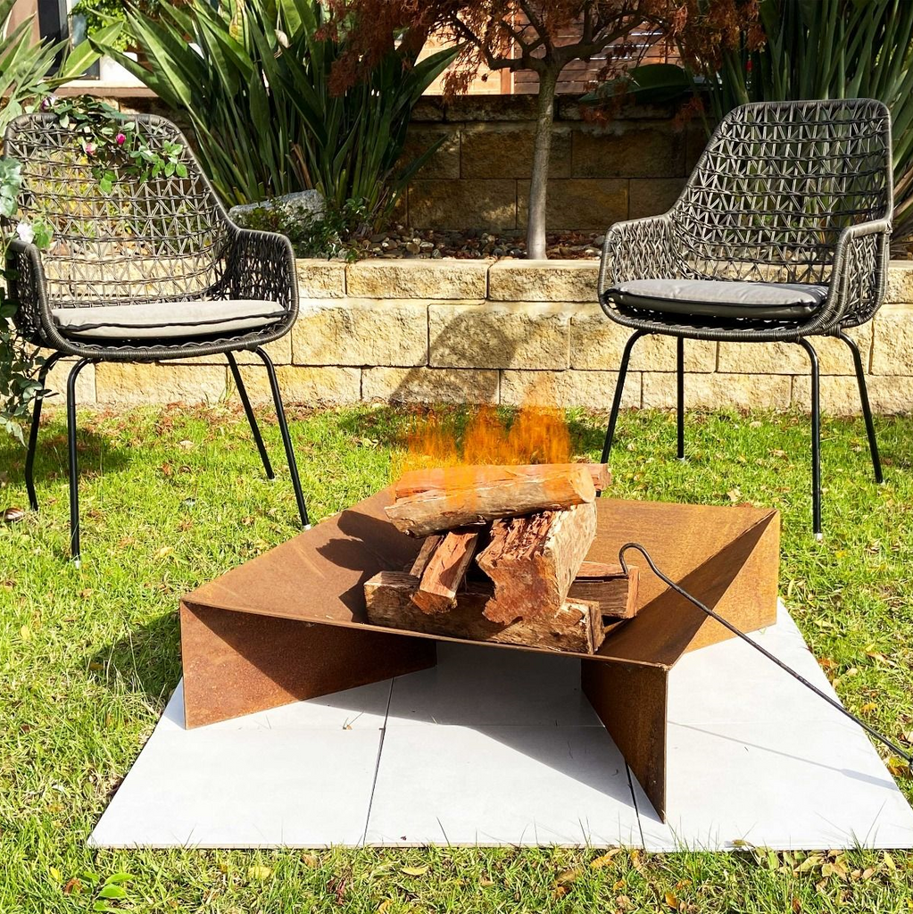 Fuji Rust FirePit with a fire burning in a garden setting and poker