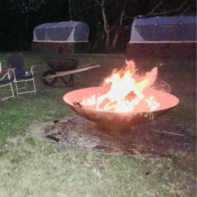 The 1500mm Cauldron Fire Pit at camp site with fire burning