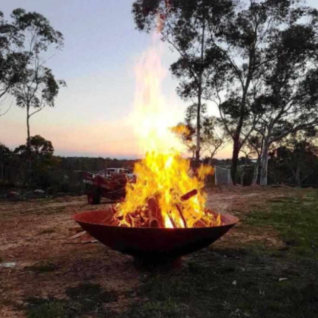  The Cauldron Fire Pit 1500mm with fire burning in rural setting