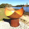 The Chalice Fire Pit beside the sea in natural rust finish