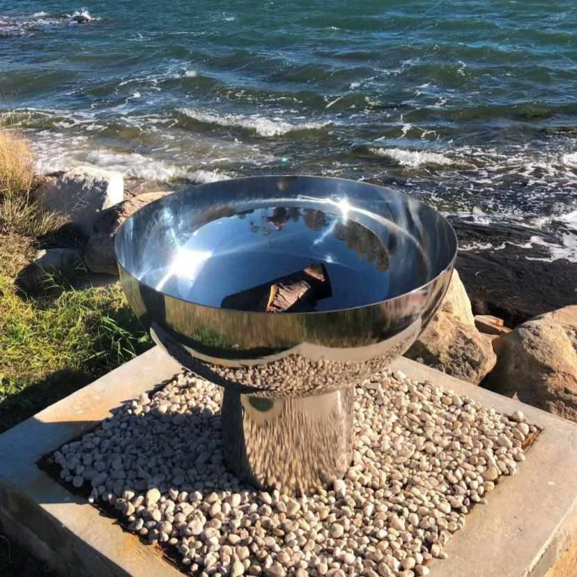 The Goblet Stainless Steel Fire Pit at the seaside on a 30cm high stand