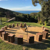 The Goblet Stainless Steel Fire Pit in the middle of log seats