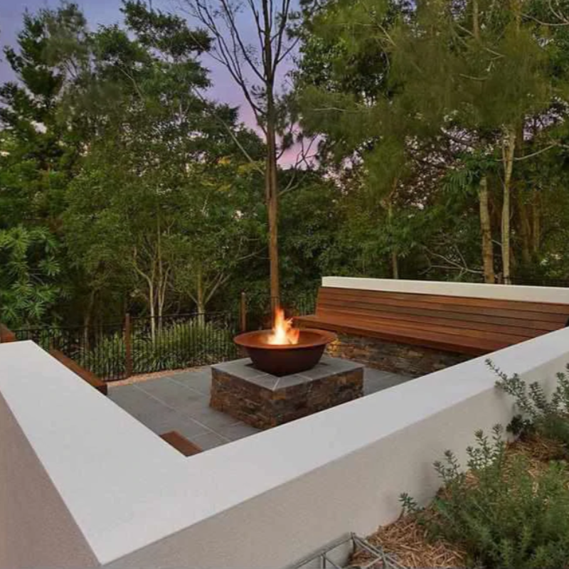 The Teppanyaki Fire Pit in a garden setting with fire burning