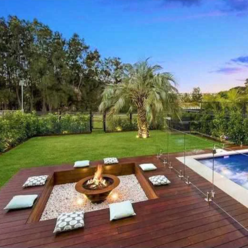 The Teppanyaki Fire Pit in backyard beside a pool with fire burning