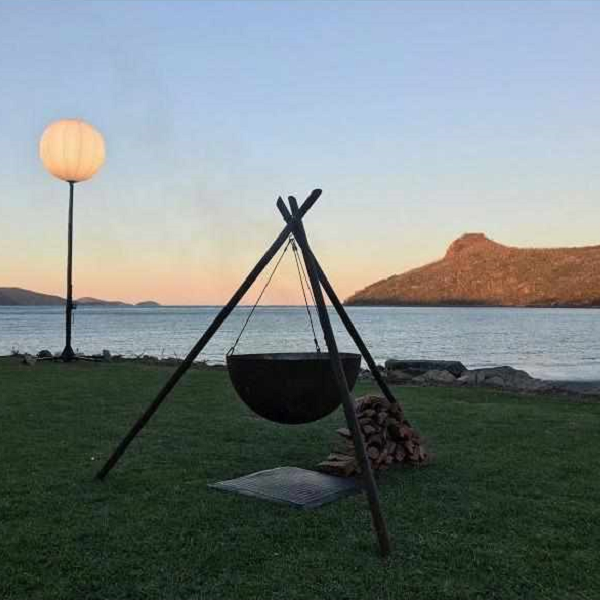 The Tripod Fire Pit on lawn at a lake side